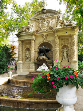 Visiting the Medici Fountain in Jardin du Luxembourg in Paris on a sunny day with flowers blooming around the water