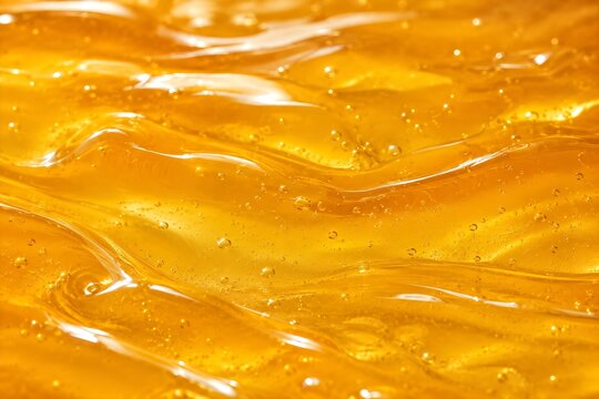 Golden transparent manuka honey background, clear texture with bubbles, 45 degree view, full frame, close up. 