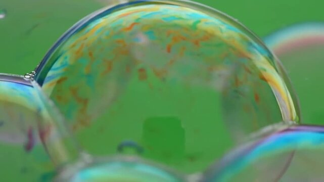 Close-up of colorful soap bubbles floating in the air against a green background