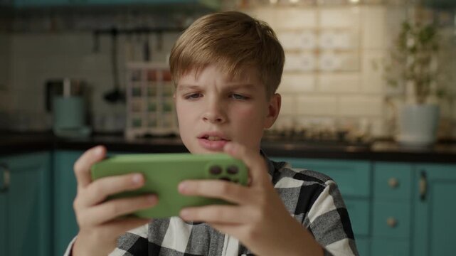 Boy Playing Mobile Games and Reacting Emotionally