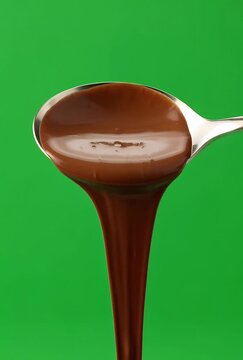 Smooth Chocolate Syrup Poured Onto A Spoon With A Green Background Close Up Studio Shot