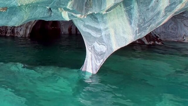 Experience the pristine beauty of Patagonia's Marble Caves. Azure glacial waters gently caress the intricately carved marble arches, a natural wonder shimmering under daylight.
