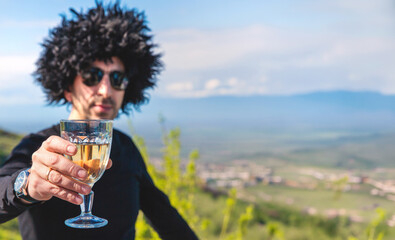 Obraz premium Georgian man in a papakhi with a glass of wine. Selective focus.