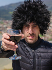 Obraz premium Georgian man in a papakhi with a glass of wine. Selective focus.