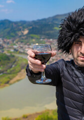 Obraz premium Georgian man in a papakhi with a glass of wine. Selective focus.
