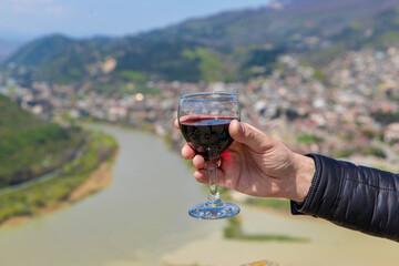 Obraz premium Georgian man in a papakhi with a glass of wine. Selective focus.