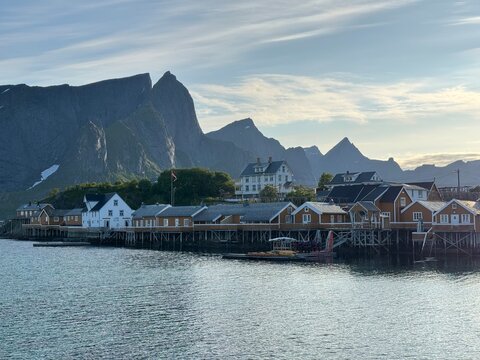 Traditional yellow rorbu cabins on the waterfront of Sakrisoy fishing village with turquoise fjord and mountains, Lofoten Islands, Norway