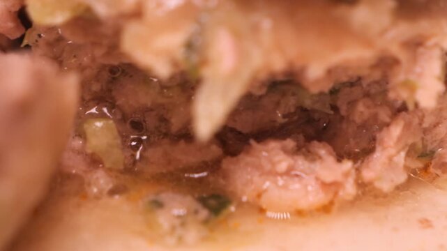 Spoon pressing down on juicy rolled dumplings
