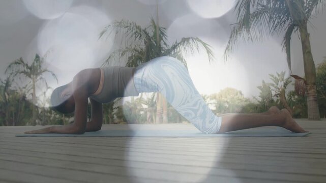 Woman starting kneeling for yoga, sliding into prone on mat, stretching spine with bokeh floating