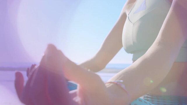 Woman seated by sea guiding hands entering view and forming mudra for wellness with animated flare