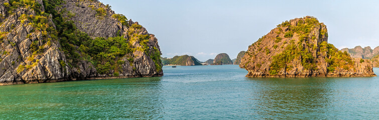 Fototapeta premium A view from a cruise ship past a Karst limestone islet in Ha Long Bay, Vietnam illuminated by the evening light