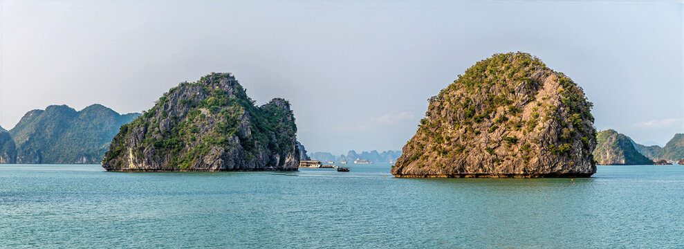 A view from a cruise ship towards a pair of Karst limestone islets in Ha Long Bay, Vietnam illuminated by the evening light
