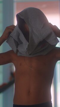 Little boy pulling clothing over face while getting dressed indoors capturing playful childhood behavior, growing independence and authentic domestic family life