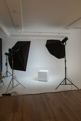 Professional photo studio setup with white cyclorama wall, softbox lighting equipment, and a white podium cube. Empty space for product photography or fashion shoots in a modern studio. © EPhotography
