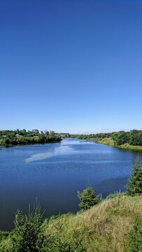 A panoramic view of the Sluch river captured from the historical archaeological site of the ancient hillfort in Hubyn village, Khmelnytskyi region, Ukraine. A peaceful summer landscape 