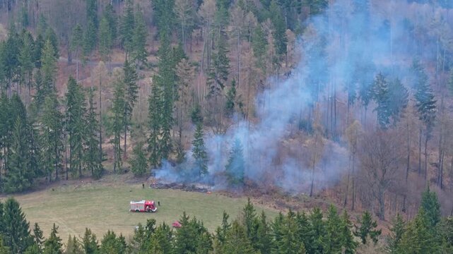 Aerial shot of forest fire caused near hunting stand with emergency response and firefighting operation in mountain landscape