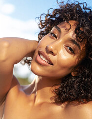 Fototapeta premium Radiant young woman with curly hair enjoying a sunny day outdoors