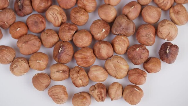 Roasted hazelnuts on white. Studio shot of crunchy hazelnuts display. Closeup of toasted hazelnuts with textured shells arranged naturally against white background
