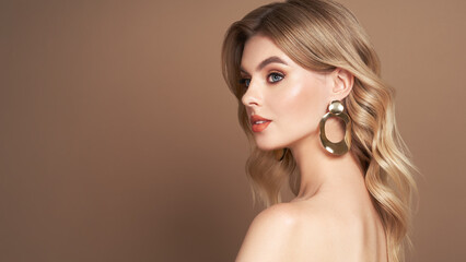 Fototapeta premium A beautiful young woman with shiny wavy blonde hair. Model with healthy skin, close up portrait. Cosmetology, beauty and spa