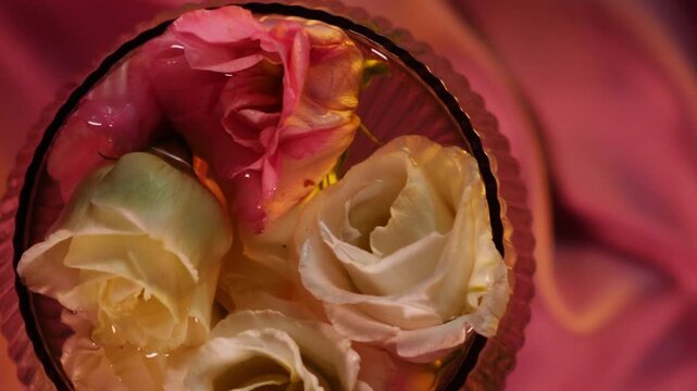 Top view of pink eustoma flowers in a glass on silk fabric