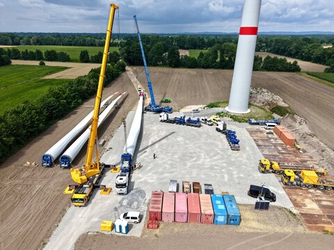 Kr&auml;ne verladen Rotorblatt f&uuml;r eine Windkraftanlage an der Baustelle eines Windparks, Windradfl&uuml;gel, Luftbild, Schwertransport, Windenergie, Logistik, Energiewende