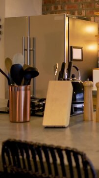 Vertical video: Panning camera moving across kitchen counter revealing copper utensils, knife block