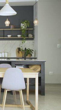 Vertical video: Panning camera revealing wood dining table and gray seats in kitchen showing layout