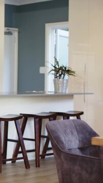 Vertical video: Camera starting, panning right across kitchen, revealing bar with 3 stools plant