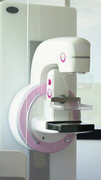 Vertical video: Panning camera revealing pink mammography unit at clinic for close view of paddle