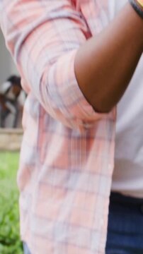 Vertical video: Leaning man reaching, adjusting grip on patio, prompted by tool, with red muffs