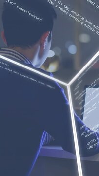 Vertical video: Programmer typing at desk activating neon cube with code wrapping across face