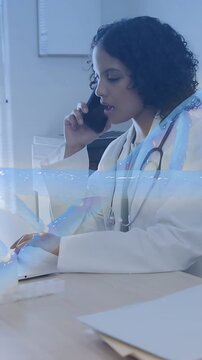 Vertical video: Dr taking call managing care while using laptop and docs, blue wave crossing her