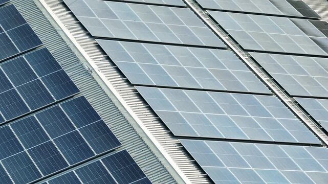 Industrial factory roof filled with solar panel systems captured by drone, reflecting sustainable energy strategies for climate resilience, net zero goals, and eco friendly development. 4k.
