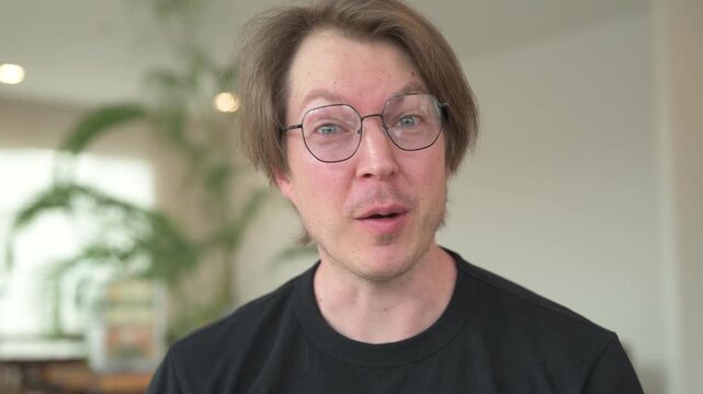 Portrait of Scandinavian Northern European man influencer vlogging and talking while sitting in coffee shop cafe restaurant