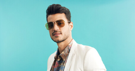 Fototapeta premium Man, portrait or retro fashion with sunglasses in studio for old style or trend on a blue background. Male person, vintage or stylish outfit with shades for swag, nostalgic look or throwback on space