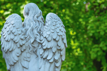 Naklejka premium White cemetery angel statue seen from behind with detailed wings. Copy space for design or text.