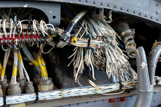 Closeup of dismantled vintage aircraft wiring and avionics inside airframe compartment. Industrial aviation recycling scene shows tangled cables, connectors, electronics and damaged technical systems