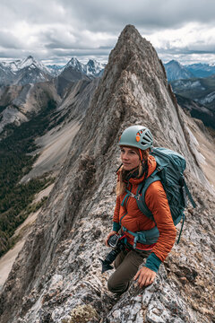 Female Adventure Enthusiast Conquers Mountain Summit: Scenic View of Her Climbing Journey in the Great Outdoors