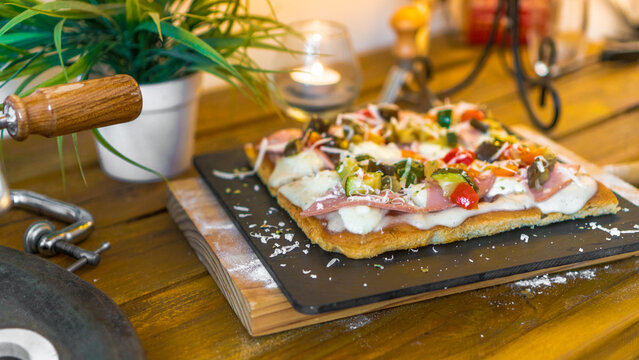 Rectangular pizza with ham, cheese and vegetables on wooden table