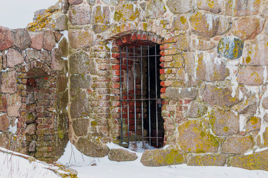Ancient stone ruins with a barred brick archway in winter snow. Hammershus Bornholm Denmark