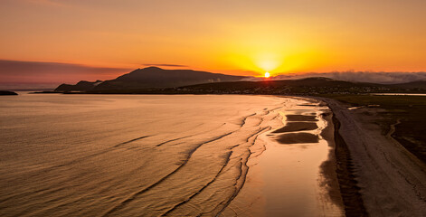 Fototapeta premium Aerial sunset view of Keem Beach on Achill Island, County Mayo, Ireland. Golden Atlantic light over the horseshoe bay, sand and cliffs of the Wild Atlantic Way.