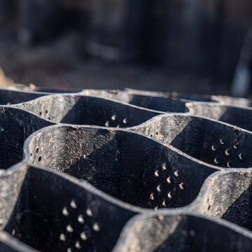 Close-up of black perforated geocell geosynthetic structure on construction site