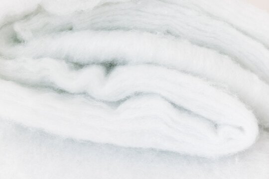 Folded White Synthetic Padding Fabric. Soft Polyester Batting Fiber Material Texture.