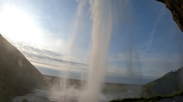 Looking out from behind Seljalandsfoss waterfall at sunset, Iceland