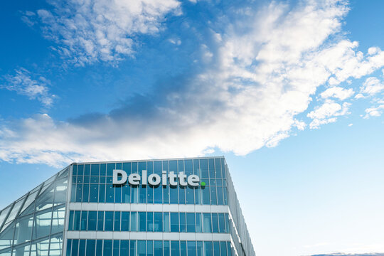 Netherlands - April 17, 2026: The Deloitte logo displayed on the glass facade of "The Edge" office building in Amsterdam's Zuidas business district under a bright blue sky.
