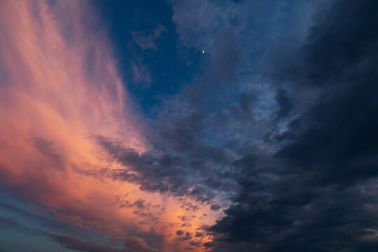 cielo nuvoloso, al tramonto, diviso a met&agrave; da nuvole scure e nuvole chiare e colorate