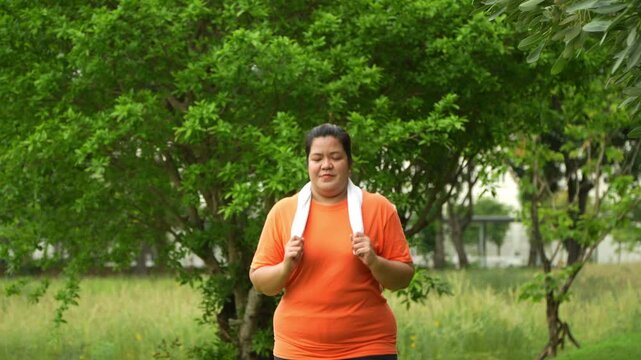 Determined Stance: A person, poised after exercise, stands with a towel around their neck amid a natural, verdant landscape, their posture communicating dedication and healthy living.