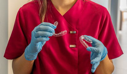 Dental professional holding clear aligners for teeth straightening
