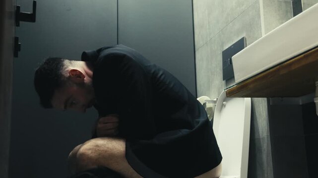 Office worker experiencing digestive discomfort in bathroom interior. Concept healthcare, stress and unhealthy lifestyle.
