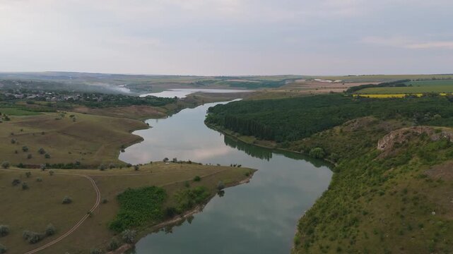 Cinematic aerial view of the Ciuhur river bay at the Costesti-Stinca reservoir in Varatic, Moldova. Drone flight over calm waters and ancient limestone reefs in the Prut river basin.